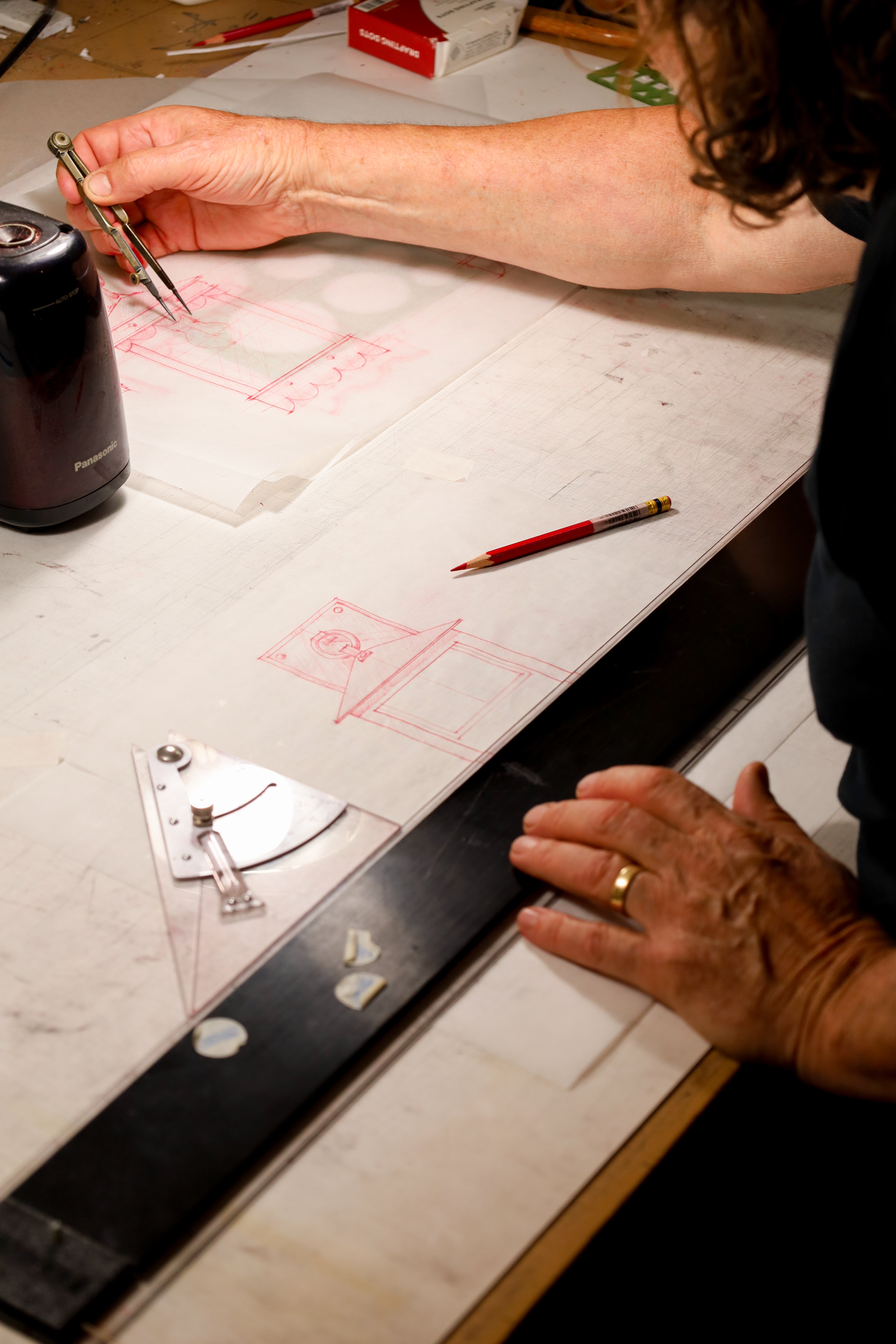 Person using drafting tools on a table with blueprints