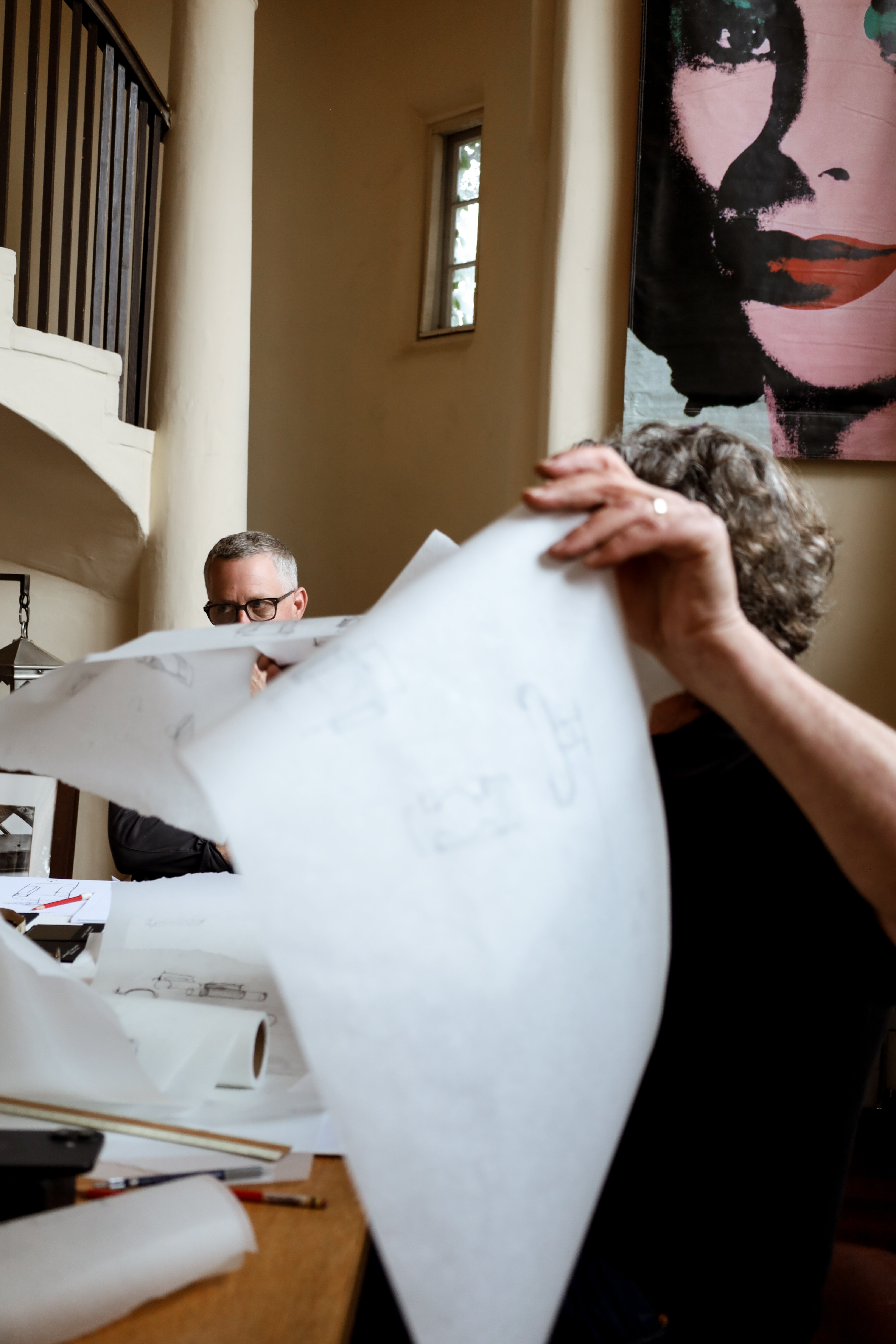 Architect holding up architectural drawings in design meeting in Santa Barbara, California.